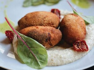 Croquetas de papa sobre crema de queso